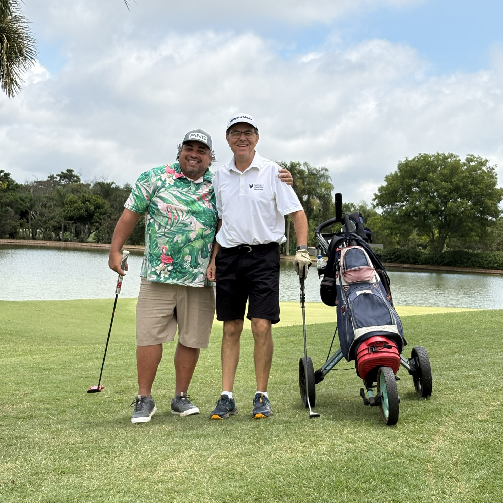 Dois golfistas no campo do Damha Golf Club com um carrinho de tacos
